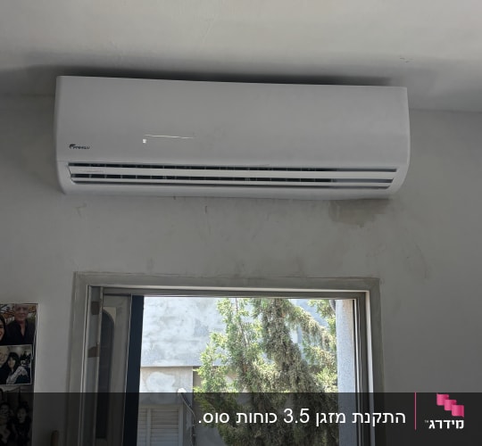 מזגן מותקן על קיר ליד חלון פתוח